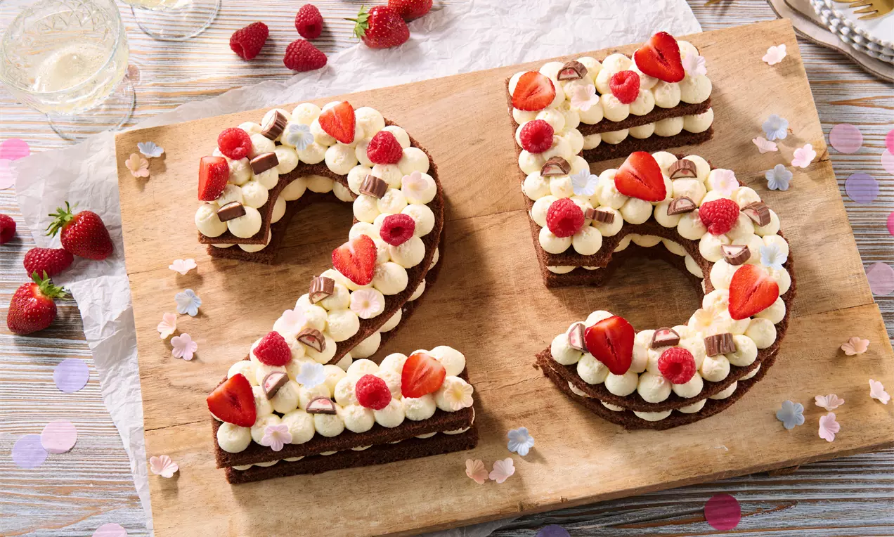 Dunkelbraune Zahlentorte in Form von 25, geschichtet mit Creme, dekoriert mit Erdbeeren, Himbeeren, Schokolade und kleinen Blüten.