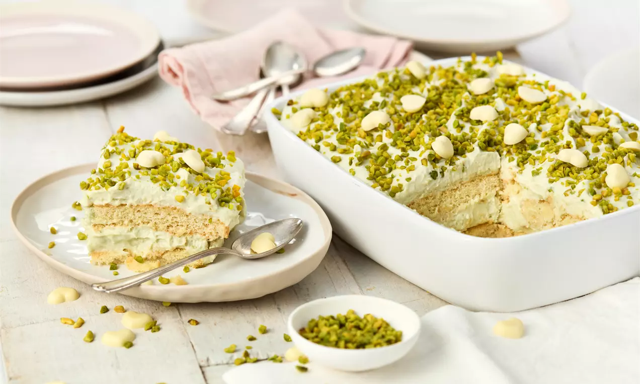 Pistazien Tiramisu mit hellgrüner Mascarpone-Pistaziencreme, goldbraunen Biskuitschichten, gehackten Pistazien und Kakaopulver garniert