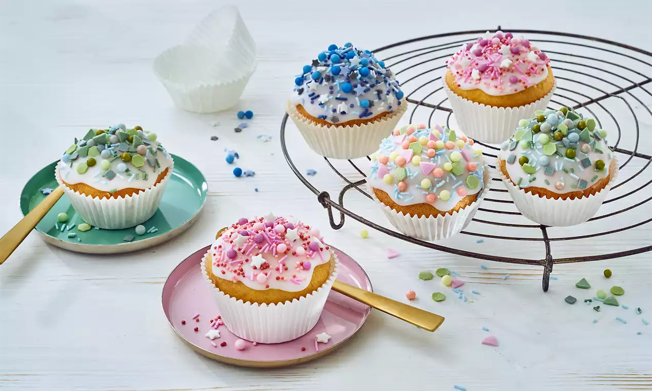 Schnelle Muffins: helle goldbraune Muffins, locker und saftig, garniert mit Puderzucker, Beeren und Minzblatt auf Holzbrett