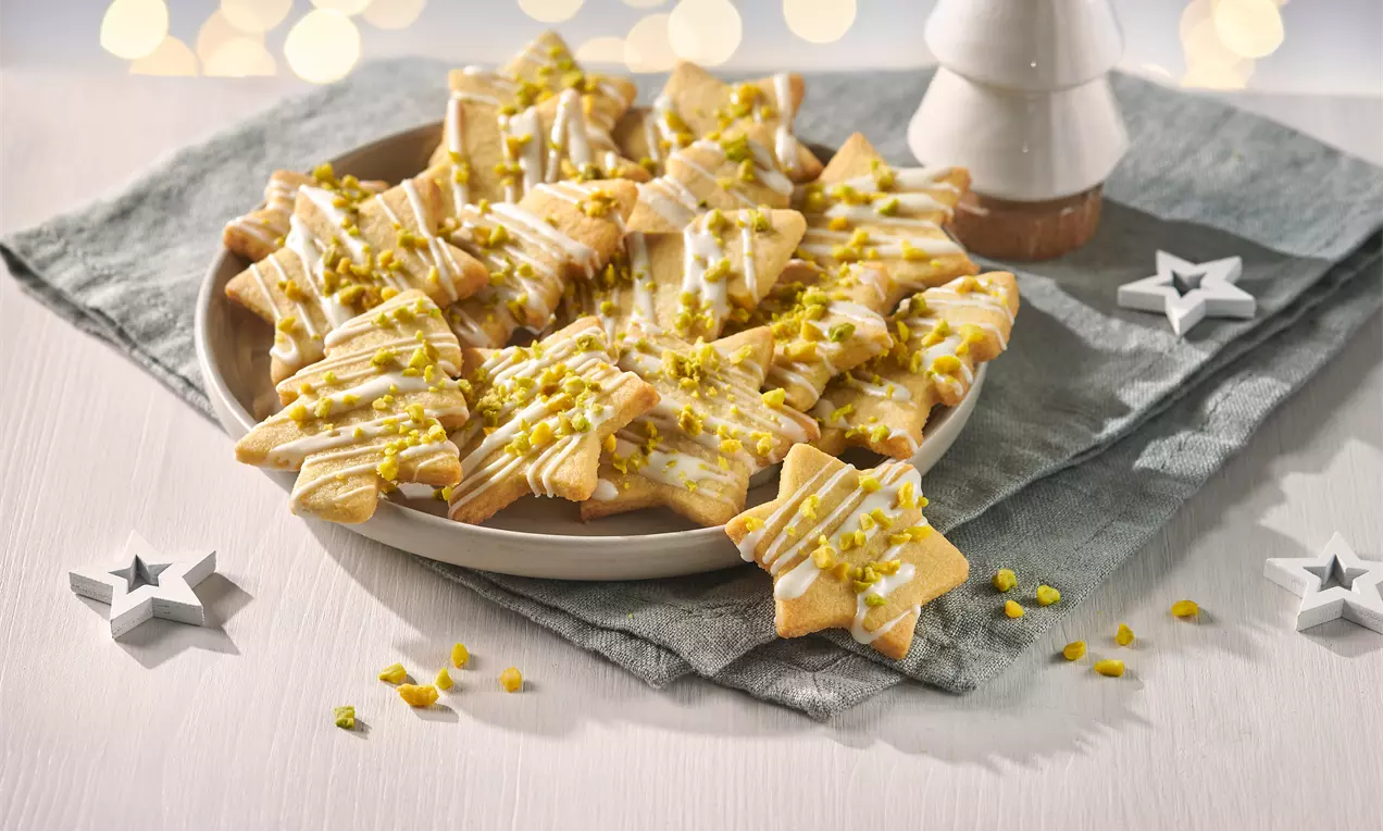 Pistazien Plätzchen aus Mürbeteig mit Pistaziencreme, weißer Glasur und gehackten Pistazien – aromatische Weihnachtskekse zum Ausstechen und Verzieren.