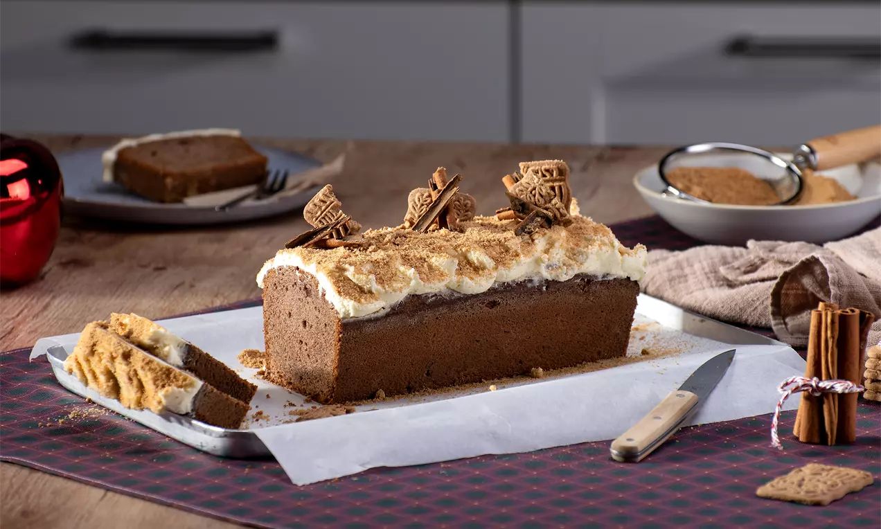 Spekulatius-Frischkäse-Kuchen mit goldbrauner Kruste, cremigem weißen Frischkäse-Topping, Spekulatiusbröseln und Zimt auf einem Teller