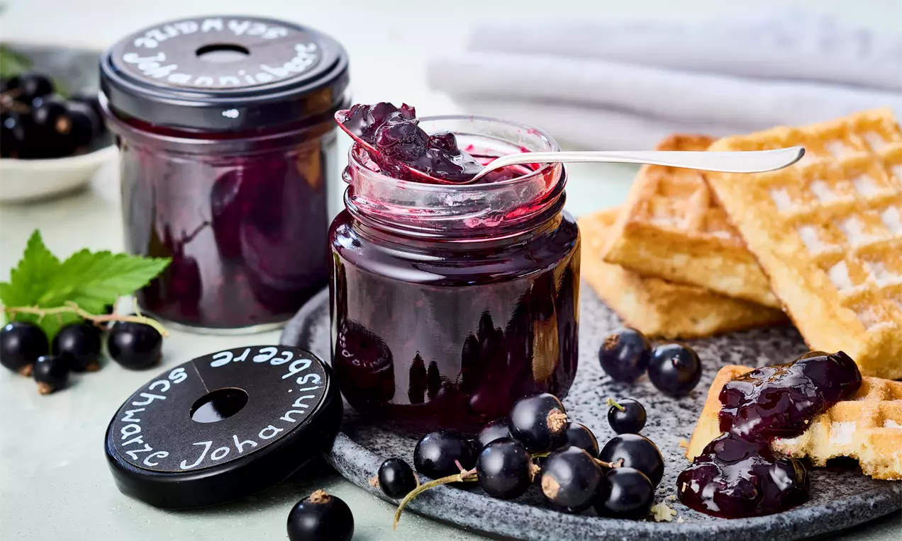 Schwarze Johannisbeermarmelade im offenen Glas mit Teelöffel – fruchtiges Rezept mit intensivem Aroma. Einfach selbst gemacht, perfekt für Frühstück, Brot, Brötchen oder Käse.