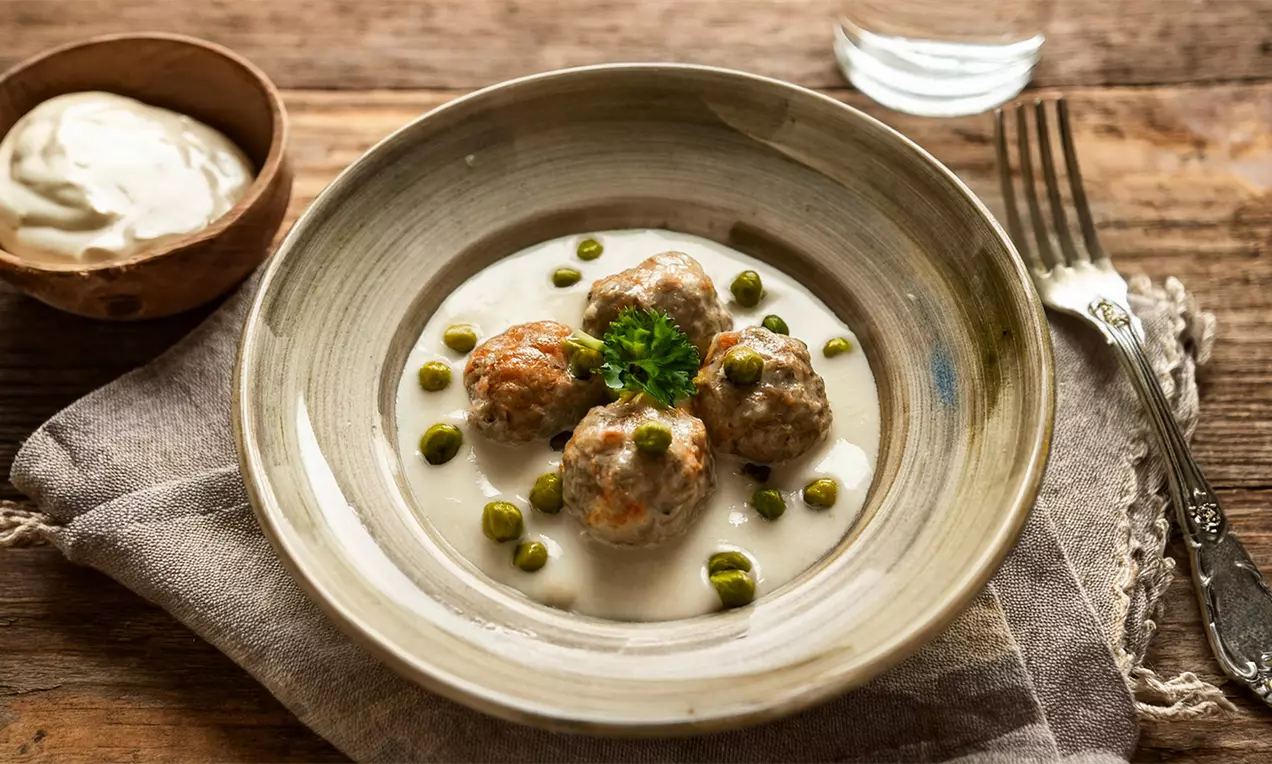 Ein Teller mit 4 zarten Königsberger Klopse in heller Soße mit Kapern und Kräutern - Klassisches Rezept für Königsberger Klopse in heller Soße mit Kapern., AI-labeled image