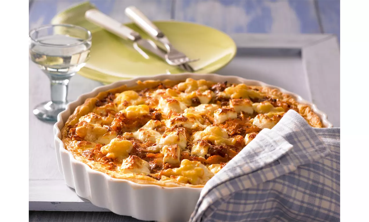 Goldbraune Weißkohl-Blätterteig-Quiche mit knusprigem Rand, saftiger Füllung und überbackenem Käse in weißer Tarteform mit Geschirrtuch drapiert