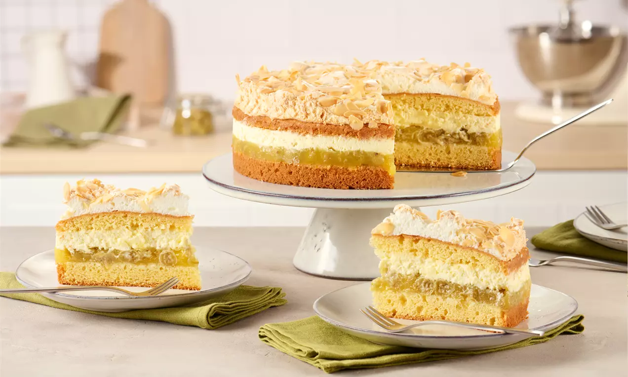 Stachelbeertorte mit goldbraunem Biskuitboden, einer Schicht Stachelbeeren, Sahne und luftiger Baiserhaube auf einer Tortenplatte angerichtet