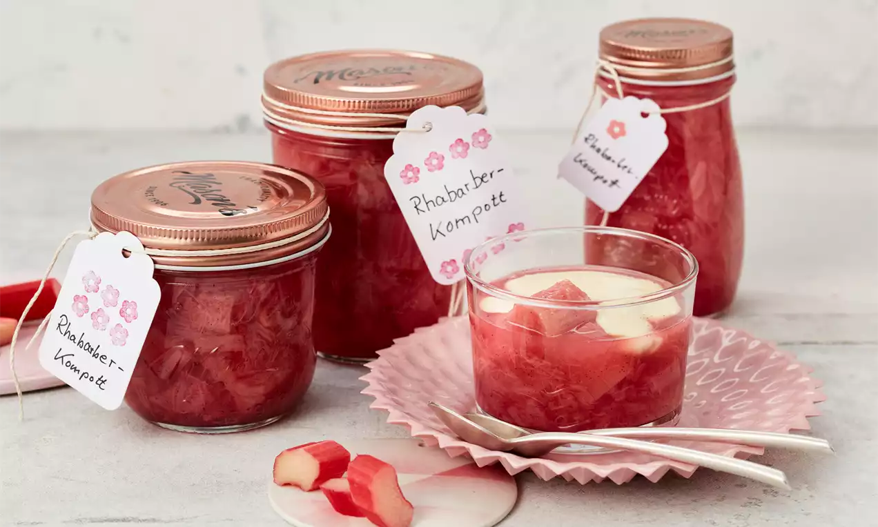 Rhabarber-Kompott in Glas mit glänzendem rosa-rotem Fruchtmus, Vanilleschote und frischen Rhabarberstücken als Vorratsdessert
