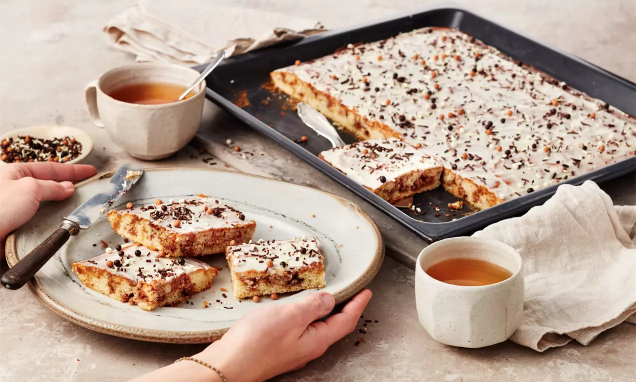 Zimtschnecken Blechkuchen mit saftigem Rührteig, Zimt-Swirl und Frischkäseguss – einfaches Rezept für fluffigen Kuchen zum Teilen und Genießen.
