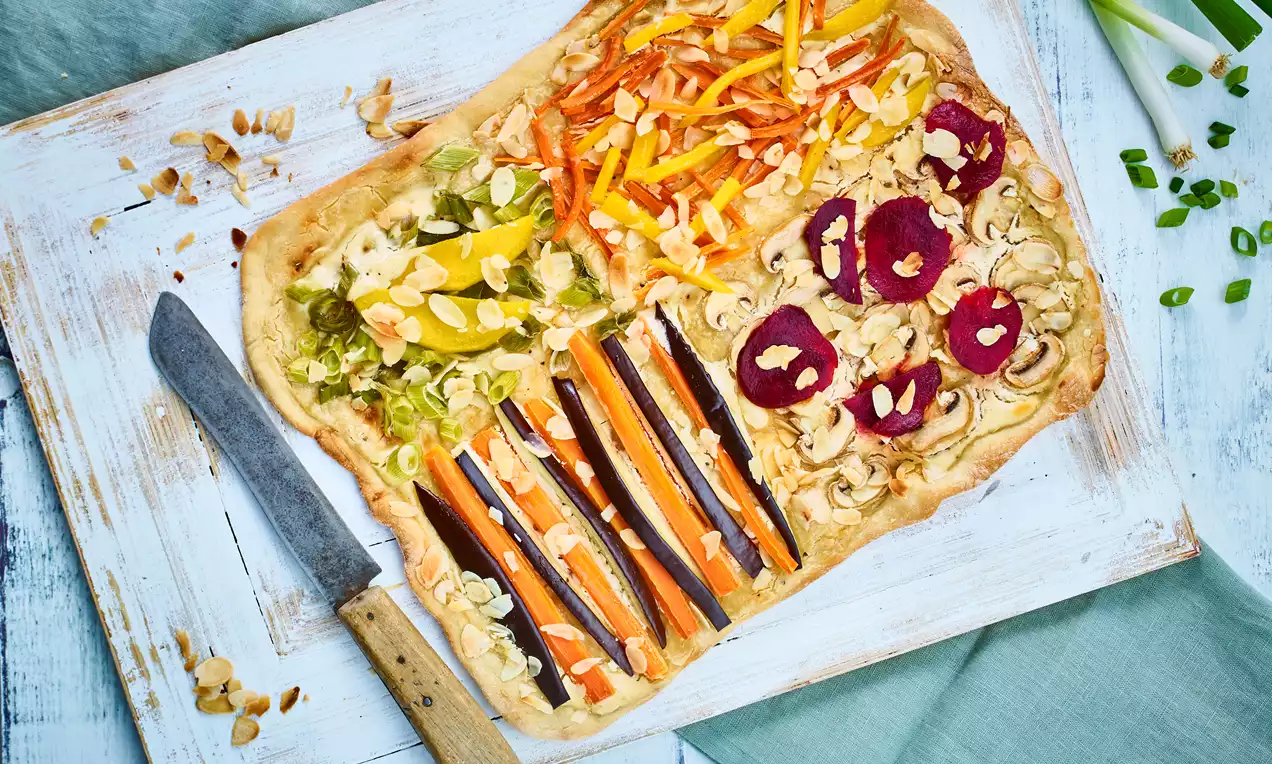 Knuspriger veganer Flammkuchen mit buntem Gemüsebelag aus Mango, Möhren, Rote Bete, Aubergine und Mandeln – einfaches Rezept für schnellen, pflanzlichen Genuss.