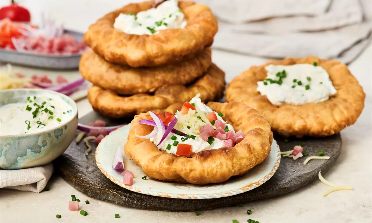 Ungarischer Langos: außen knusprig, innen fluffig, frisch frittiert und serviert mit cremigem Crème-fraîche-Dip, Schnittlauch und optionalem Käse – ein herzhafter Klassiker zum Selbermachen.