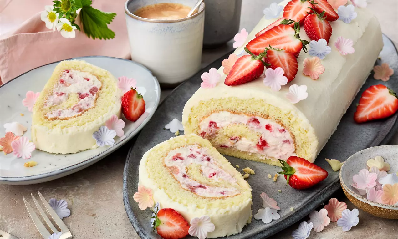 angeschnittene Erdbeer-Quark-Rolle mit lockerem Biskuit, frischer Quarkcreme und saftigen Erdbeeren – Biskuitrolle ohne Gelatine. Einfaches Rezept für Kaffeezeit.