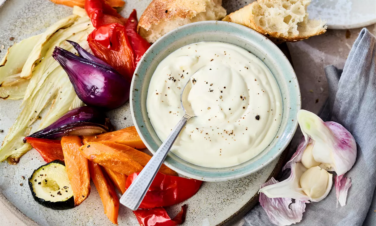Schale mit Löffel an Aioli ohne Ei mit Knoblauch, Crème fraîche und Mayonnaise – cremiger Dip für Brot, Gemüse oder Grillgerichte. Einfaches Aioli Rezept zum Selbermachen und Genießen.