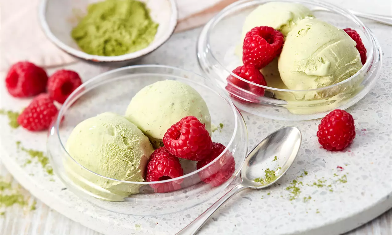 Zartgrüne Kugeln cremiges Matcha-Eis mit grünem Matchapulver, serviert mit frischen Himbeeren – einfaches Rezept ohne Eismaschine für erfrischenden Sommergenuss.