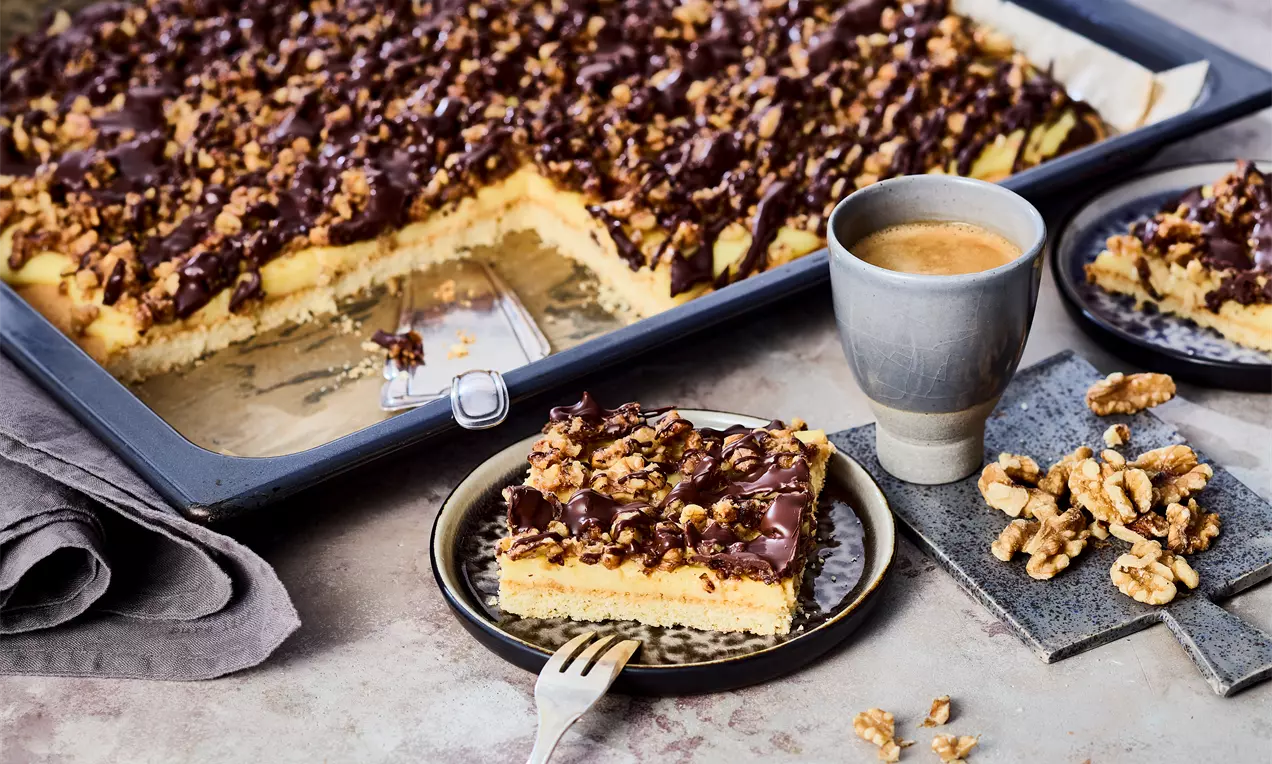Fress-mich-dumm-Kuchen mit Mürbeteig, Vanillepudding-Creme und karamellisierten Walnüssen, Schokoguss – einfaches Blechkuchenrezept für Kaffeetafel, Dessert oder süße Genussmomente.