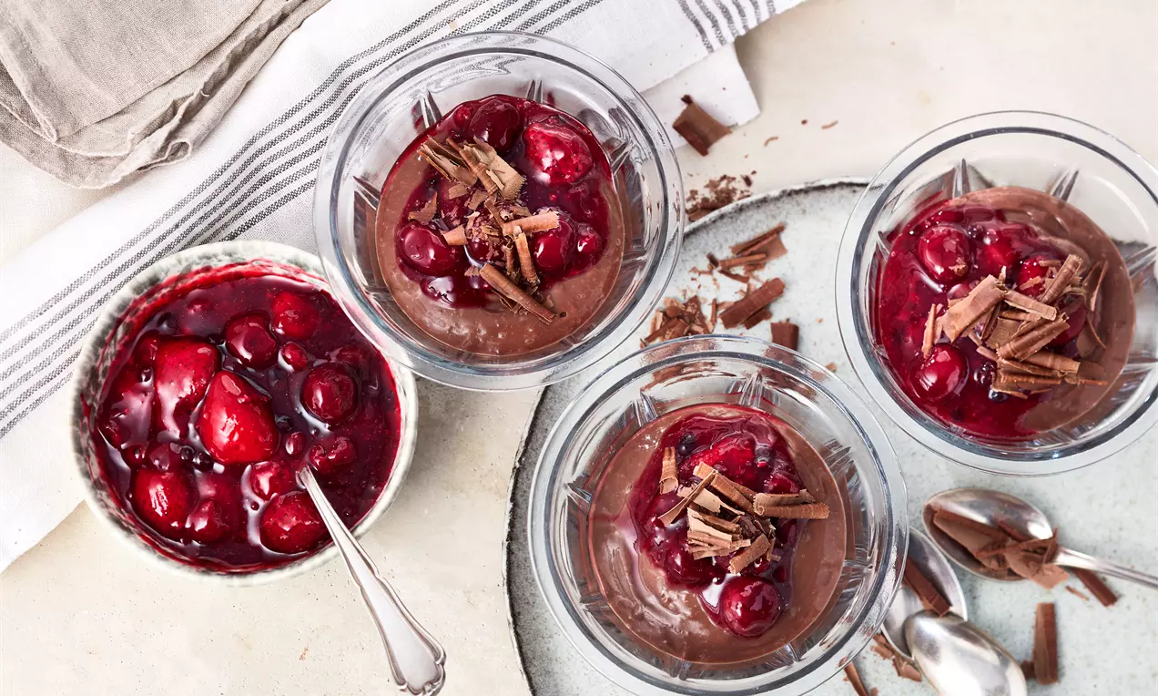 Cremiger veganer Schokopudding aus Mandeldrink, verfeinert mit fruchtiger Roter Grütze und dekorativen Schokospänen – ein schnelles, pflanzliches Dessert für Schokoladenliebhaber.