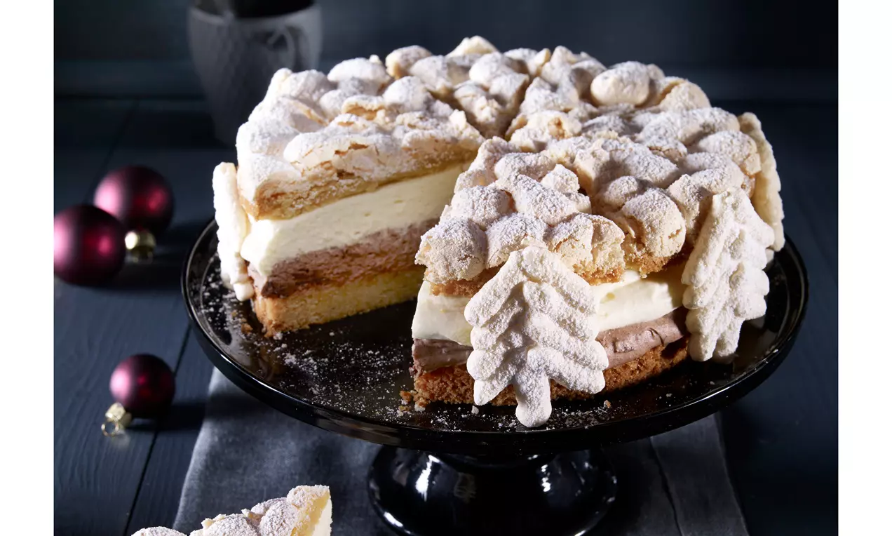 Schneetorte mit heller Cremefüllung und Schoko-Schicht auf dunkler Kuchenplatte, oben mit geformten Tannen und Puderzucker bestäubt