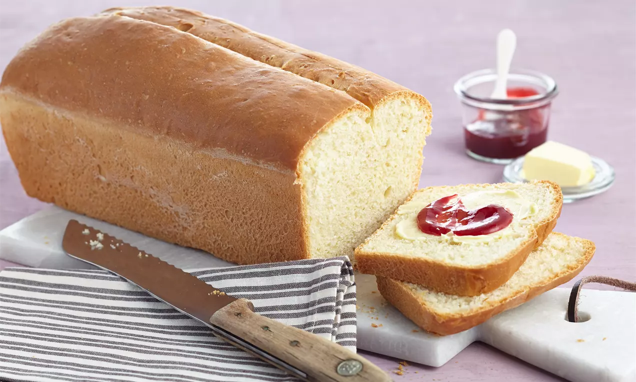 Quarkbrot mit Backpulver als goldbraunes Kastenbrot mit hellen, weichen Scheiben, auf Holzbrett serviert mit Butter und frischen Kräutern