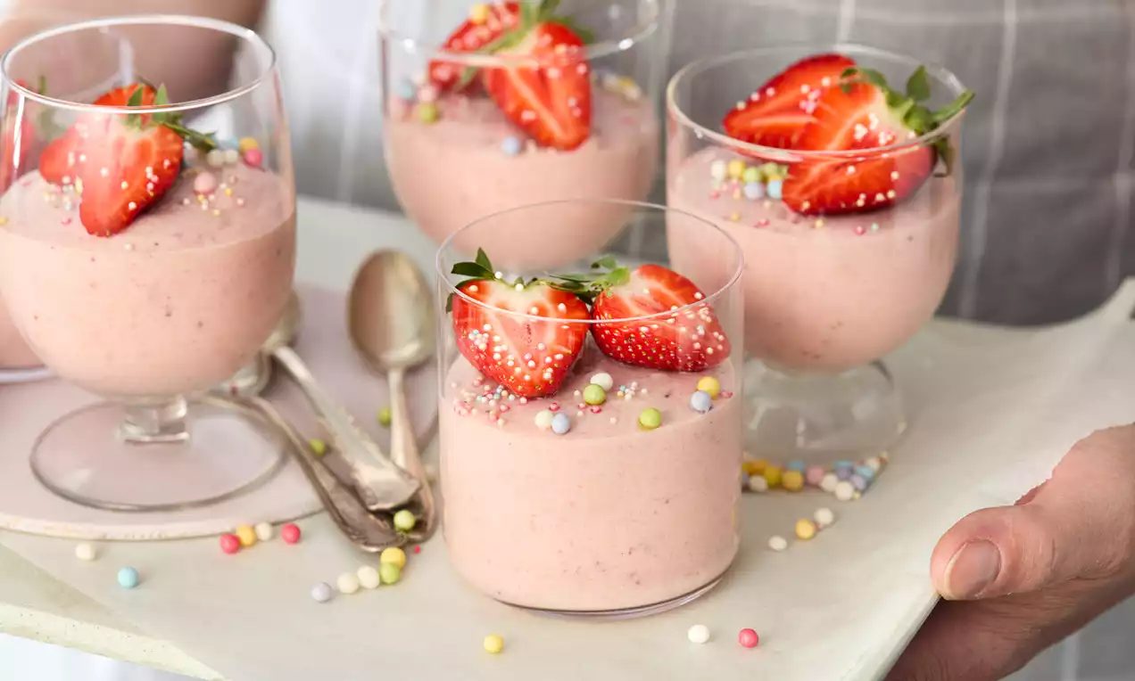 Erdbeer-Buttermilch-Dessert im Glas mit Schichten aus rosa Erdbeerpüree, hellcremiger Buttermilchcreme, frischen Erdbeerscheiben und Minzblatt